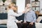 Young high-skilled pleasant woman doctor putting on nebulizer mask on face of her elderly bearded male patient to make