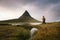 Young hiker with a backpack looks at the Kirkjufell mountain in Iceland