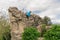 Young hiker climbing on abandoned fortress stone wall with cloudy sky background. Solo traveler concept