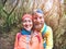 Young hiker couple taking selfie photo at inside forest track - Happy millennial people having fun in tour excursion - Travel,