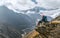 Young hiker female backpacker sitting on the cliff edge and enjoying mountain peaks view during Everest Base Camp EBC trekking