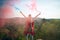 Young hiker sending colorful smoke signal to mountaineers, back view