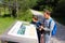 Young hikers observe a sign of the park on the path along the lake, Lago di Dobbiaco, Dolomites, Italy