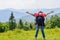 Young hiking woman standing on top of the mountain with valley on the background