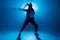 Young hip-hop female dancer performing solo on the stage in blue neon lights