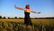 Young hippie woman in dress raising hands while goes among wheat meadow and enjoys freedom. Carefree punk girl with