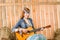 Young hippie woman play guitar in barn