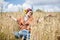 Young hippie woman with red burgundy hair, wearing boho style clothes, sitting in middle of wheat field, meditating, thinking,
