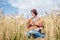 Young hippie woman with red burgundy hair, wearing boho style clothes, sitting in middle of wheat field, meditating, thinking,