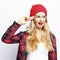 young hipster blonde woman with bright sexy make up wearing stylish urban plaid shirt and red hat