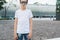 Young hipster boy in sunglasses dressed in white t-shirt is stands outdoor. Mock up. Space for logo, text, image.