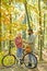 Young hipster couple having a romantic date in the forest standing one against the other near bike. First really serious