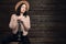 Young hipster girl having fun and posing with small ukulele guitar on a wooden studio background.