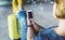 Young hipster girl sitting at airport and put feet in yellow boot on suitcase traveling in Europe, female hands texting message