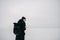 Young hipster guy dressed in black in the winter on the frozen lake with a cup of coffee in hand