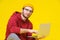 Young hipster man sitting on the floor holding laptop in red hoodie studying or working. Smart freelancer caucasian man