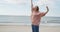 Young hipster woman standing on top of the hill rising hands against the sea