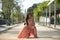 Young, Hispanic, beautiful, brunette, young woman in an elegant salmon-colored dress, posing independent and empowered, sitting on