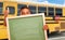 Young Hispanic Boy with Blank Chalkboard Near School Bus