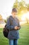 Young Hispanic Boy Walking Outdoors With Backpack Texting on Cell Phone