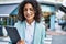 Young hispanic business woman wearing professional look smiling confident at the city holding worker clipboard