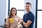 Young hispanic couple business workers drinking coffee at office