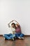 Young hispanic couple doing roof symbol with hands sitting on the floor at empty new home