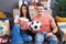 Young hispanic couple football hooligans holding ball and eating popcorn looking positive and happy standing and smiling with a