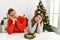 Young hispanic couple sitting at the table on christmas sleeping tired dreaming and posing with hands together while smiling with