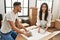 Young hispanic couple smiling happy unpacking cardboard box at new home