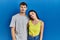 Young hispanic couple standing together over blue background looking sleepy and tired, exhausted for fatigue and hangover, lazy