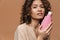 Young hispanic curly woman posing with beauty product