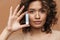 Young hispanic curly woman posing and showing lipstick