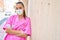 Young hispanic doctor woman wearing medical mask leaning on the wall at street of city