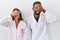 Young hispanic doctors standing over white background smiling and laughing with hand on face covering eyes for surprise