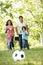 Young Hispanic Family Playing Football In Park