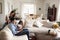 Young Hispanic family sitting on sofa reading a book together in their living room