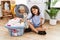 Young hispanic girl doing laundry holding socks pointing to the back behind with hand and thumbs up, smiling confident