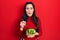 Young hispanic girl eating salad making fish face with mouth and squinting eyes, crazy and comical