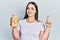 Young hispanic girl holding bottle with boiled potatoes smiling happy pointing with hand and finger to the side