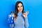 Young hispanic girl holding mouthwash for fresh breath doing ok sign with fingers, smiling friendly gesturing excellent symbol