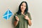 Young hispanic girl holding scotland flag smiling happy pointing with hand and finger