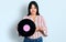 Young hispanic girl holding vinyl disc relaxed with serious expression on face