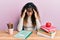 Young hispanic girl studying for school exam with hand on head, headache because stress