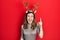 Young hispanic girl wearing deer christmas hat pointing finger up with successful idea