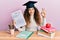Young hispanic girl wearing graduated hat holding passed test doing ok sign with fingers, smiling friendly gesturing excellent