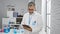 Young hispanic grey-haired man scientist using touchpad at laboratory