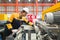 Young hispanic labor dressed in polyester jacket uniform, hardhat and protective glove checks the orderliness of the machine.