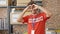 Young hispanic man activist wearing volunteer uniform doing heart gesture at charity center