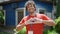 Young hispanic man activist wearing volunteer uniform doing heart gesture at park